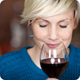 A woman smelling red wine